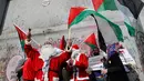 Pengunjuk rasa berkostum sinterklas (Santa Claus) memegang bendera Palestina dalam demonstrasi di Bethlehem, Tepi Barat, 23 Desember 2017. Mereka menentang kebijakan Presiden Donald Trump soal Yerusalem yang diklaim Ibu Kota Israel. (AP/Nasser Shiyoukhi)