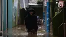 Warga melintasi banjir di kawasan Kebon Pala, Kampung Melayu, Jakarta Timur, Sabtu (16/7/2022). Karena rumahnya terendam banjir, sejumlah warga sudah mulai menyelamatkan barang-barang berharga ke tempat yang lebih tinggi. (merdeka.com/Imam Buhori)