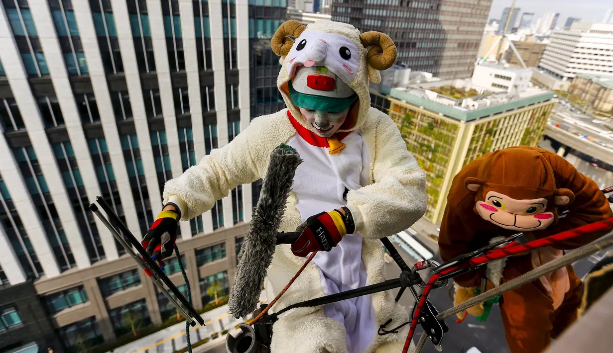 Petugas Pembersih jendela mengenakan kostum domba dan monyet saat membersihkan jendela lantai 15 sebuah hotel di Tokyo, Jepang, (21/12). Mereka mengenakan kostum mencerminkan shio hewan pada kalender Cina. (REUTERS/Thomas Peter)