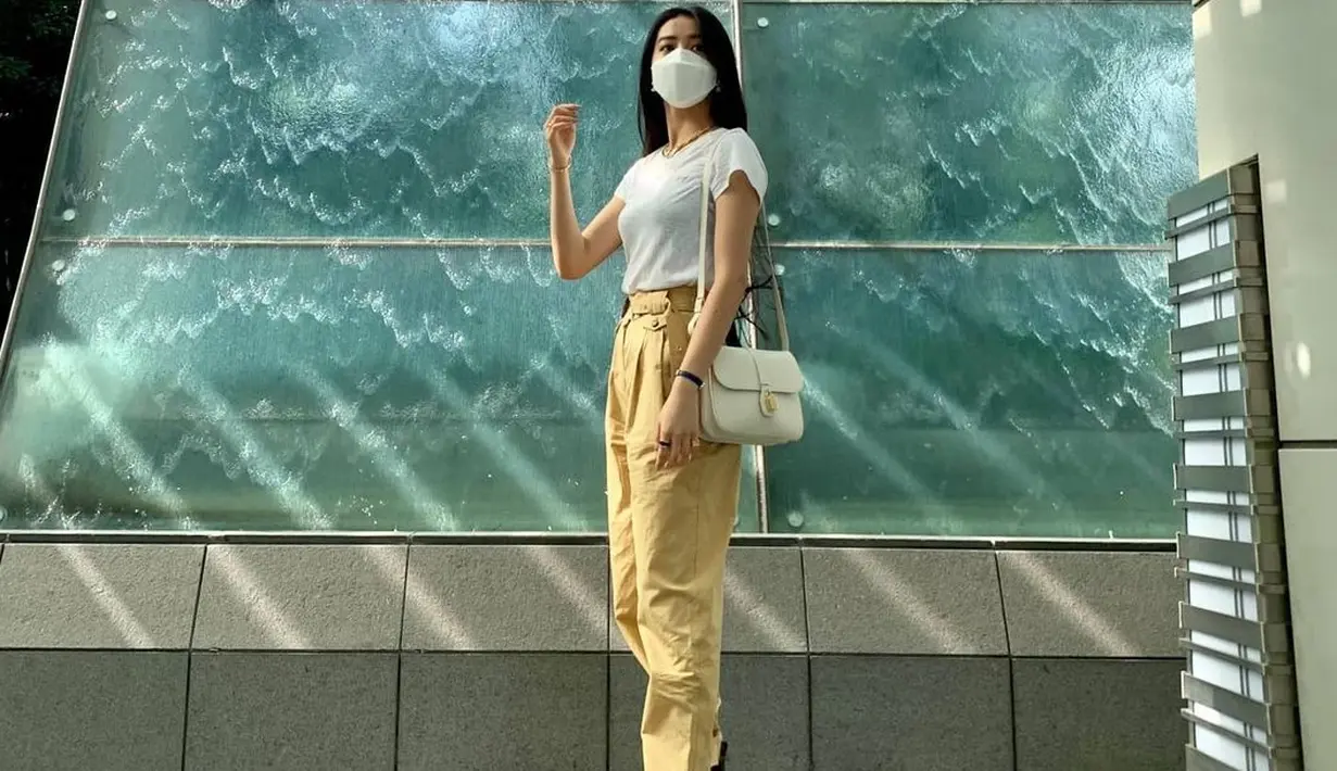 Koki terlihat mengenakan kaus putih polos dengan celana panjang berwarna khaki, dan sepatu hitam. Ia memberi sentuhan akhir yang sempurna dengan membawa Celine Tabou Bag berwarna putih. Foto: Document/Celine.