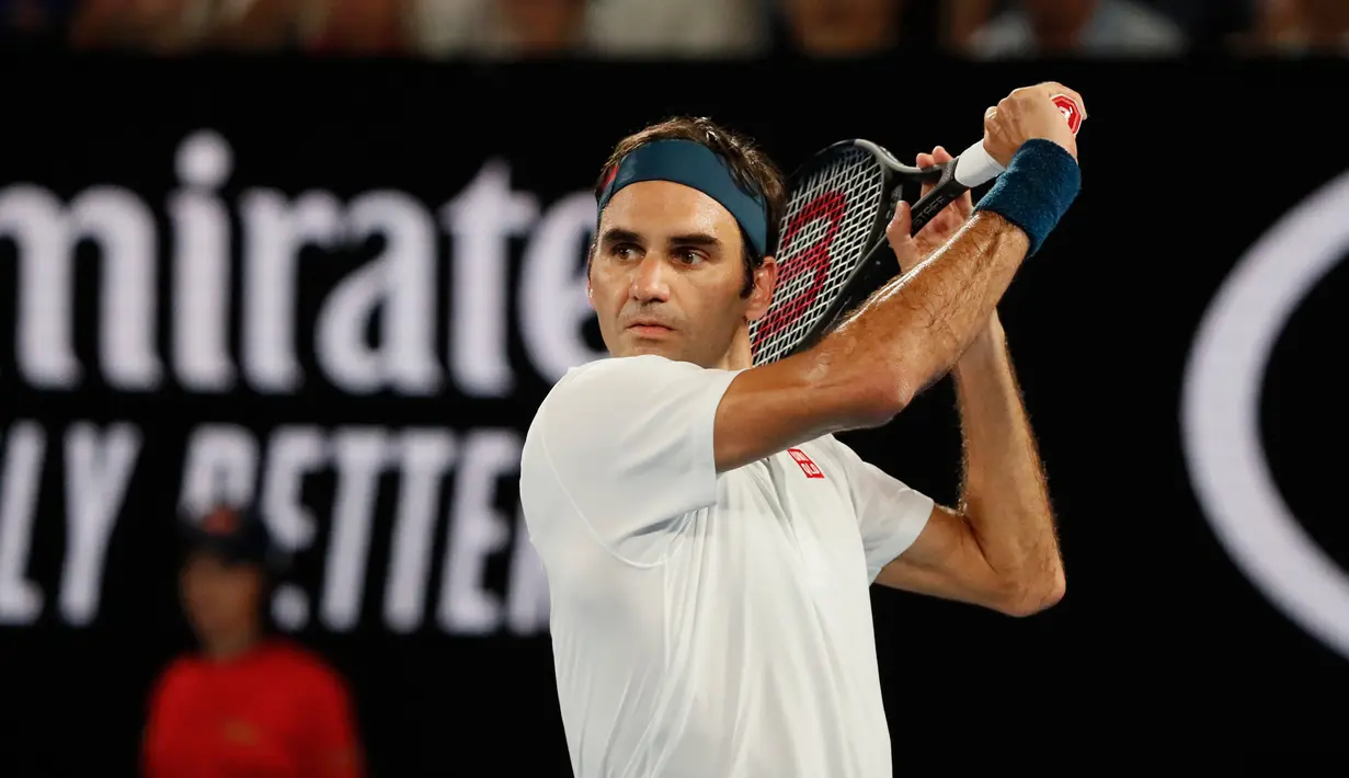 Petenis Swiss, Roger Federer mengembalikan bola ke arah Taylor Fritz dari AS dalam babak 32 besar Australia Terbuka di Melbourne, Jumat (18/1). Federer melaju mulus ke babak 16 besar setelah menang tiga set langsung 6-2 7-5 6-2. (DAVID GRAY/AFP)