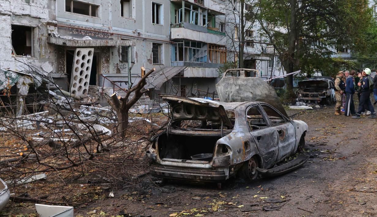 Di Zaporizhzhia, satu orang tewas dan 10 lainnya luka-luka, sementara lebih dari 70 ribu warga sempat kehilangan pasokan listrik untuk sementara. Tampak dalam foto, mobil-mobil yang terbakar dan bangunan tempat tinggal yang rusak terlihat setelah serangan Rusia di Zaporizhzhia, Ukraina, Minggu 5 Oktober 2025. (AP Photo/Kateryna Klochko)
