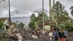 Orang-orang berjalan di tanah yang tertutup abu vulkanik setelah aliran piroklastik selama letusan Gunung Semeru di Desa Supiturang, Lumajang, Jawa Timur pada Kamis 20 November 2025. Gunung Semeru kembali mengalami erupsi pada Rabu (19/11/2025) sore. (Agus Harianto/AFP)