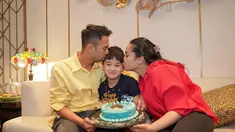 Raffi Ahmad, Nagita Slavina mencium Rafathar yang tengah memegang kue ulang tahunnya.