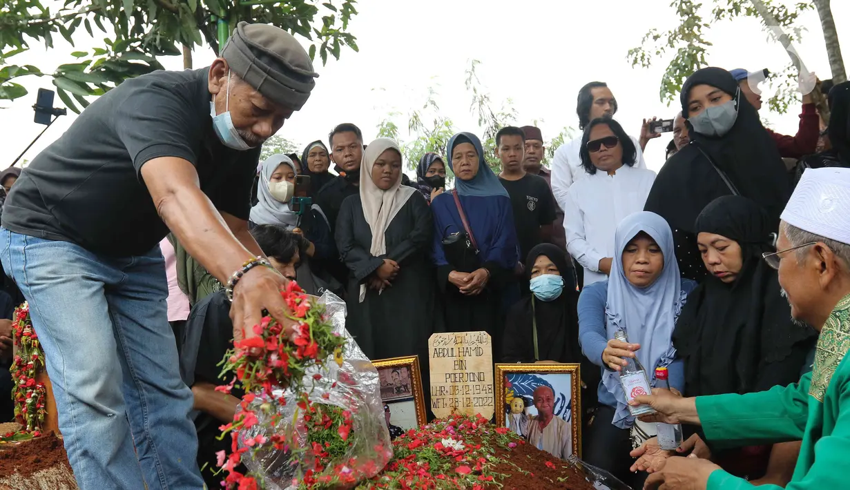Seorang kerabat menabur bunga saat pemakaman Abdul Hamid alias Pak Ogah di TPU (Tempat Pemakaman Umum) Jatisari, Bekasi, Jawa Barat, Kamis (29/12/2022). Pak Ogah salah satu pengisi suara dalam serial film Si Unyil meninggal pada (28/12/2022) di usia 74 tahun. (Liputan6.com/Herman Zakharia)