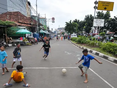Sejumlah anak bermain sepak bola di Jalan Tambak, Manggarai, Jakarta, Jumat (22/7). Minimnya lahan bermain, sejumlah anak manfaatkan jalanan untuk bermain. (Liputan6.com/Yoppy Renato)
