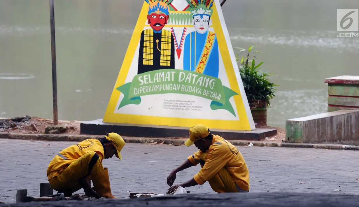 Petugas melakukan perbaikan jalan masuk Setu Babakan, Jakarta, Jumat (14/7). Setu Babakan akan menjadi lokasi pelaksanaan Lebaran Betawi 2017 yang akan digelar pada 21 - 23 Juli 2017. (Liputan6.com/Helmi Fithriansyah)