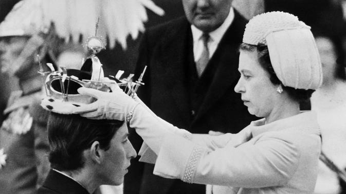 Dalam file foto ini diambil pada 01 Juli 1969 Ratu Elizabeth II meletakkan mahkota pada putranya Pangeran Charles selama penobatannya sebagai Pangeran Wales yang baru di Caernarfon. (Photo by CENTRAL PRESS / AFP)