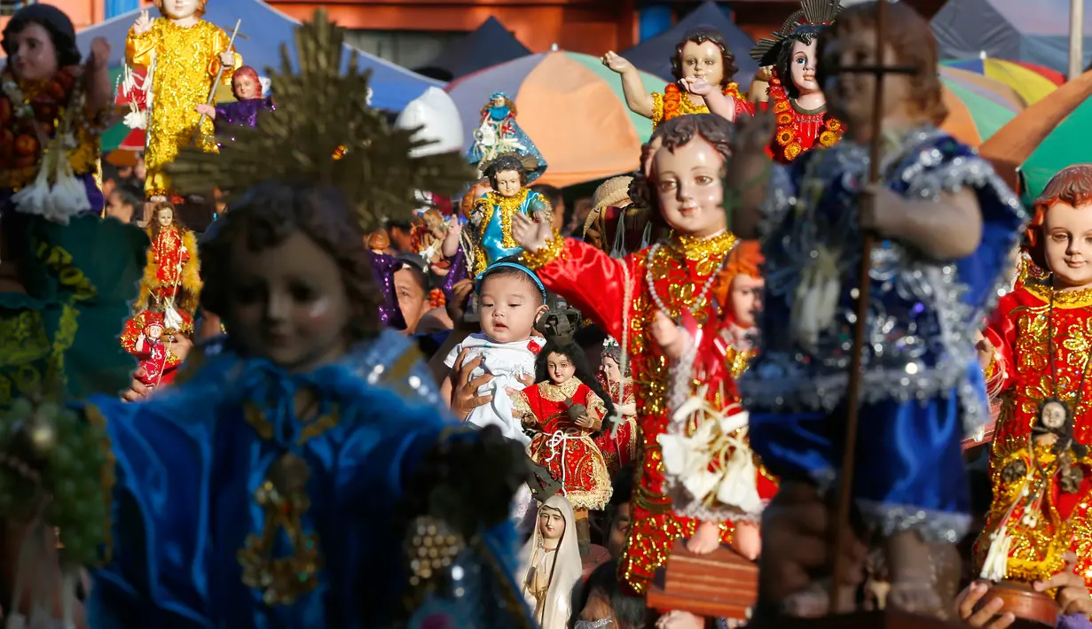 Seorang anak diangkat diantara patung simbol Bayi Yesus saat pemberkatan di Manila, Filipina (21/1). Santo Nino merupakan salah satu perayaan devosional paling besar di Filipina, yang dirayakan pada Minggu ketiga bulan Januari. (AP Photo / Bullit Marquez)
