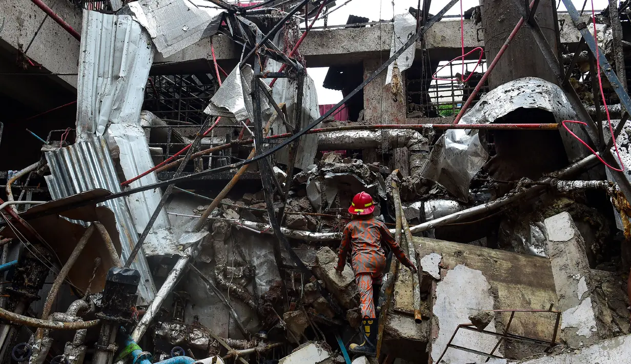 Seorang pemadam kebakaran memeriksa dan mencari korban di puing-puing bekas ledakan pabrik di Dhaka, Bangladesh (4/7). Akibat ledakan tersebut 10 orang tewas dan puluhan lainnya mengalami luka cukup serius. (AFP Photo/Munir Uz Zaman)