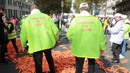 Demonstran membuang sebanyak 1,2 ton wortel ke jalanan depan kantor Kementerian Kesehatan di Paris, Rabu (4/10). Pemerintah ingin meningkatkan kesadaran masyarakat Paris agar berhenti merokok dengan cara menaikan harga rokok. (AFP PHOTO/JACQUES DEMARTHON)