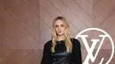 Sophie Turner memilih mengenakan mini dress leather lengan panjang dipadukan knee boots warna senada. Sambil membawa handbag hitam leather. [dok. Louis Vuitton]
