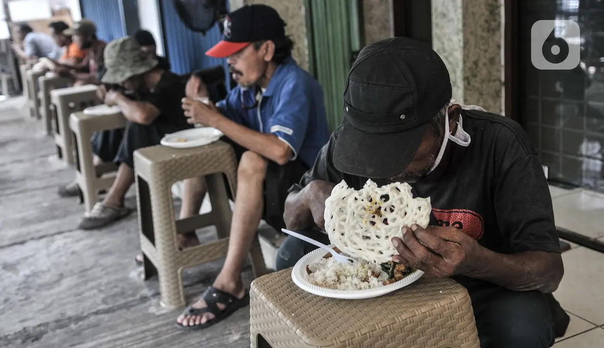 Warga menikmati makan siang gratis di Jalan Basuki Rachmat, Cipinang Muara, Jakarta, Senin (8/3/2021). Layanan solidaritas makan gratis ini juga menerapkan protokol kesehatan seperti pemberian jarak antar bangku, kewajiban memakai masker, serta pengecekan suhu tubuh. (merdeka.com/Iqbal S Nugroho)