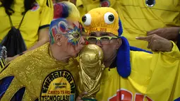 Dua pendukung Kolombia mencium miniatur piala dunia jelang dimulainya pertandingan kualifikasi sepak bola Piala Dunia 2018 melawan Paraguay di Barranquilla, Kolombia, (5/10). (AFP PHOTO/Luis Acosta)