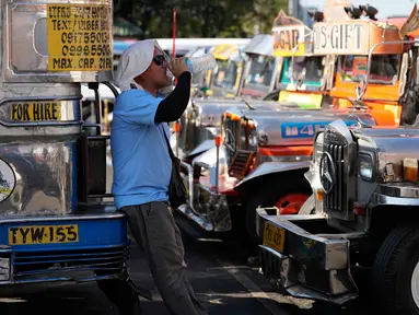 Seorang pengemudi jeepney beristirahat sambil minum air di terminal kota Pasay, Filipina, pada Senin, 23 Maret 2026. (AP Photo/Aaron Favila)