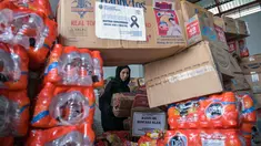 Seorang relawan mengemas perbekalan untuk dikirimkan ke daerah-daerah terdampak banjir di Badan Penanggulangan Bencana Daerah (BPBD) Sidoarjo, Provinsi Jawa Timur, pada Jumat 5 Desember 2025. Pemerintah Provinsi Jawa Timur akan memberangkatkan total 26,5 ton bantuan logistik untuk korban bencana di Sumatera Utara dan Aceh. (JUNI KRISWANTO/AFP)
