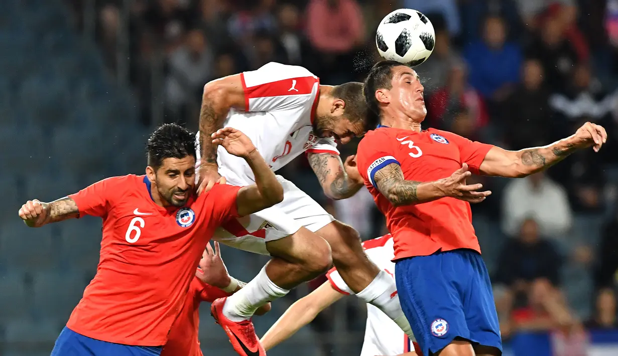 Aksi pemain Serbia, Aleksandar Mitrovic (tengah) saat duel dengan dua apemain Chili pada laga uji coba di Merkur Arena, Graz, Austria, (4/6/2018).  Serbia kalah dari Chili 0-1. (AFP/Joe Klamar)