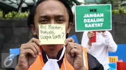 Seorang peserta aksi menunjukan tulisan nama tokoh yang terlibat kasus suap saat Car Free Day dikawasan Bunderan HI, Jakarta, Minggu (12/2). Aksi tersebut untuk menanggapi kasus Hakim Mahkamah Konstitusi, Patrialis Akbar. (Liputan6.com/Faizal Fanani)