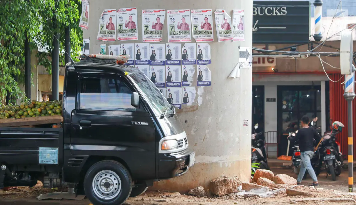 Sebuah mobil parkir dekat alat peraga kampanye calon legislatif yang menempel di sepanjang tiang penyangga Jalan Tol Desari, Jakarta, Kamis (25/4). Meskipun Pemilu serentak telah selesai, namun masih banyak APK di sejumlah sudut Ibu Kota dan menjadi sampah visual. (Liputan6.com/Immanuel Antonius)
