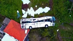 Kondisi sebuah bus pariwisata berisi rombongan turis dari Jerman yang terguling di Kota Canico, Pulau Madeira, Portugal, Rabu (17/4). Kecelakaan terjadi di mana bus yang mengangkut 55 otang turis terguling saat membelok dari jalan sempit yang curam. (STRINGER / AFP)