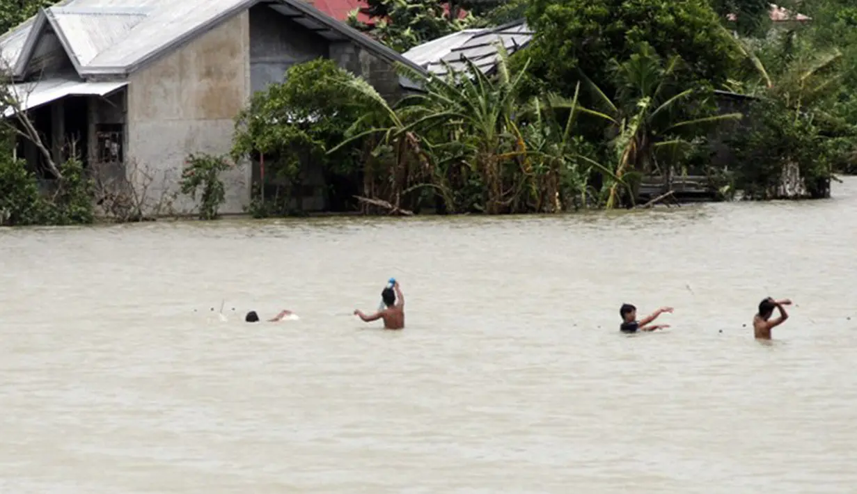 Sejumlah warga Filipina memeriksa jaring ikan yang mereka pasang saat banjir melanda wilayah mereka di Kota Condon, Ilocos sur, Filipina, Senin (24/8/2015). Banjir tersebut akibat hujan deras yang dibawa oleh Topan Goni. (AFP Photo)