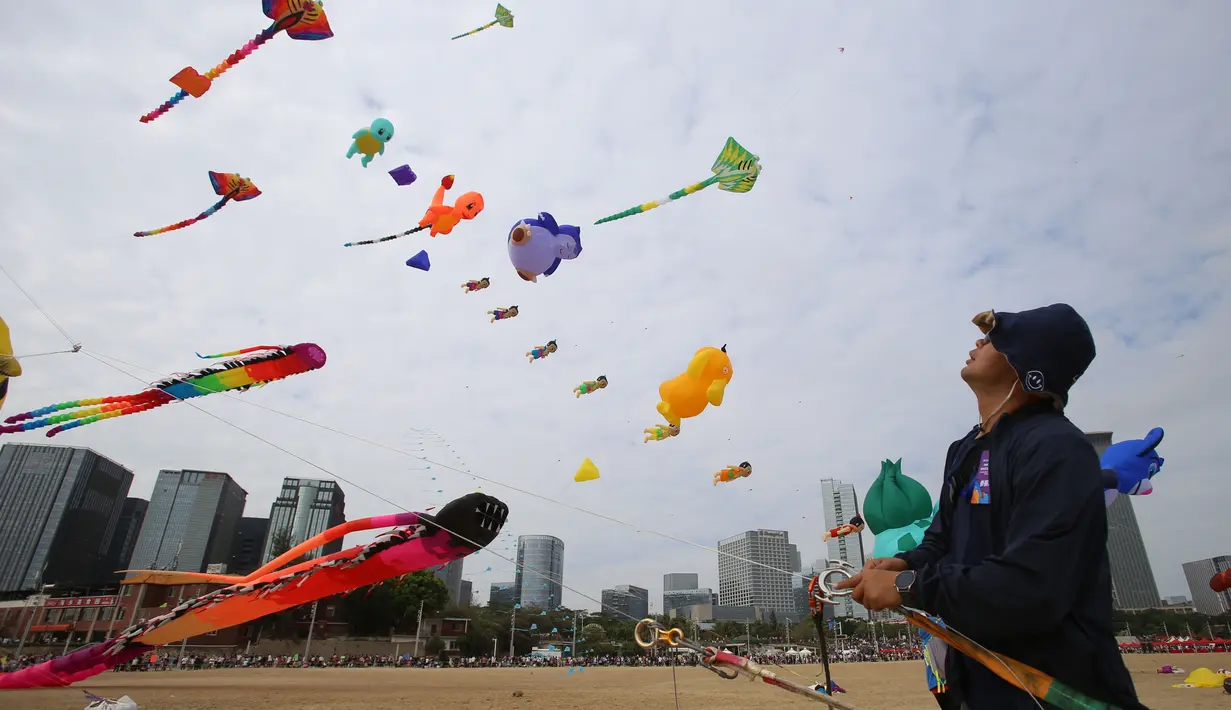 Seorang pria menerbangkan layang-layang dalam festival layang-layang di Xiamen, Provinsi Fujian, China tenggara (21/11/2020). Ratusan layang-layang diterbangkan peserta menghiasi langit wilayah China tenggara. (Xinhua/Zeng Demeng)