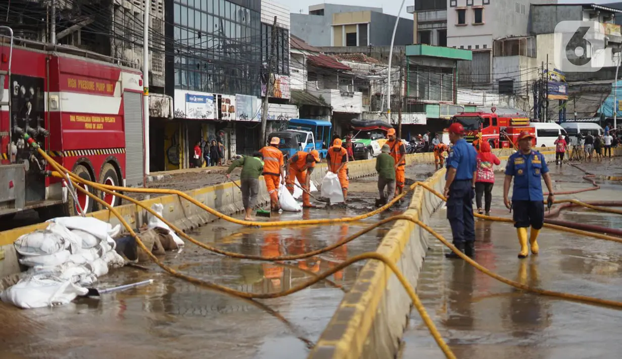 Petugas Penanganan Prasaran dan Sarana Umum (PPSU) membersihkan lumpur yang mengendap di sepanjang Jalan Jatinegara Barat, Kampung Melayu, Jakarta Timur, Kamis (2/1/2020). Petugas melakukan bersih-bersih menyusul mulai surutnya banjir di kawasan tersebut. (Liputan6.com/Immanuel Antonius)