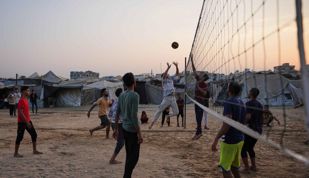 Anak-anak muda Palestina bermain voli di kamp tenda pengungsian di Zawayda, Jalur Gaza tengah, Selasa 4 November 2025. Beberapa anak muda Palestina bermain voli di kamp pengungsian Zawayda, Jalur Gaza tengah, pada Selasa 4 November 2025. (AP Photo/Abdel Kareem Hana)