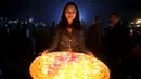 Seorang wanita membawa lilin untuk penerangan lentera kertas buatan tradisional selama festival balon Tazaungdaing tahunan di Taunggyi, Myanmar (19/11). (REUTERS/Soe Zeya Tun)