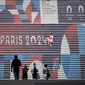 Orang-orang berpose di tangga dekat logo Olimpiade Paris 2024 di La Defense Paris, beberapa hari jelang upacara pembukaan. (AFP/Loic Venance)