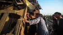 Warga memeriksa kondisi kereta usai tabrakan di dekat Kom Hamadah, Provinsi Beheira, Mesir, Rabu (28/2). Perdana Menteri Mesir Sherif Ismail memerintahkan kementerian terkait untuk mengusut tuntas penyebab kecelakaan tersebut. (AFP FOTO/Fayed El-Geziry)