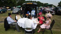 Dua wanita berbincang dengan rekannya saat makan siang di tempat parkir menjelang balap kuda di Ascot, London, (20/6). Balap kuda ini telah diadakan di Berkshire sejak tahun 1711. (AFP Photo/Daniel Leal-Olivas)