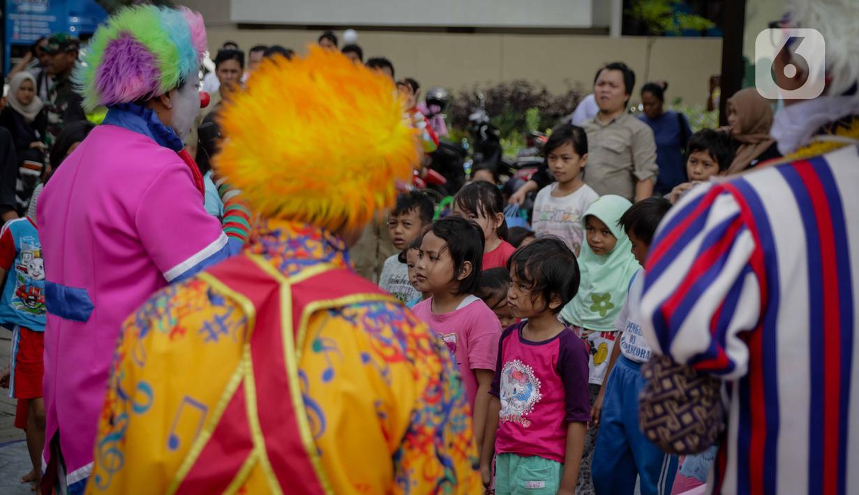 Anak-anak menyaksikan aksi badut yang tergabung dalam komunitas Aku Badut Indonesia (ABI) di pengungsian korban banjir di Gor Pangadegan, Jakarta, Selasa (7/1/2020). Trauma healing diberikan para badut sebagai bentuk kepedulian terhadap anak-anak korban banjir Jakarta. (Liputan6.com/Faizal Fanani)