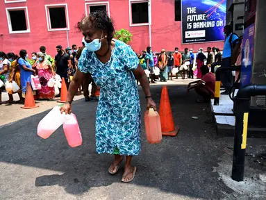 Seorang perempuan pergi usai membeli minyak tanah untuk digunakan di rumah di sebuah pompa bensin di Kolombo, Sri Lanka, 17 Maret 2022. Krisis mata uang menghambat impor bahan bakar dan kebutuhan pokok lain dari luar negeri, termasuk susu bubuk, gas untuk memasak dan bensin. (Ishara S. KODIKARA/AFP)