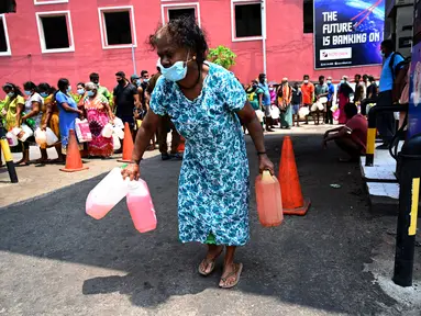 Seorang perempuan pergi usai membeli minyak tanah untuk digunakan di rumah di sebuah pompa bensin di Kolombo, Sri Lanka, 17 Maret 2022. Krisis mata uang menghambat impor bahan bakar dan kebutuhan pokok lain dari luar negeri, termasuk susu bubuk, gas untuk memasak dan bensin. (Ishara S. KODIKARA/AFP)
