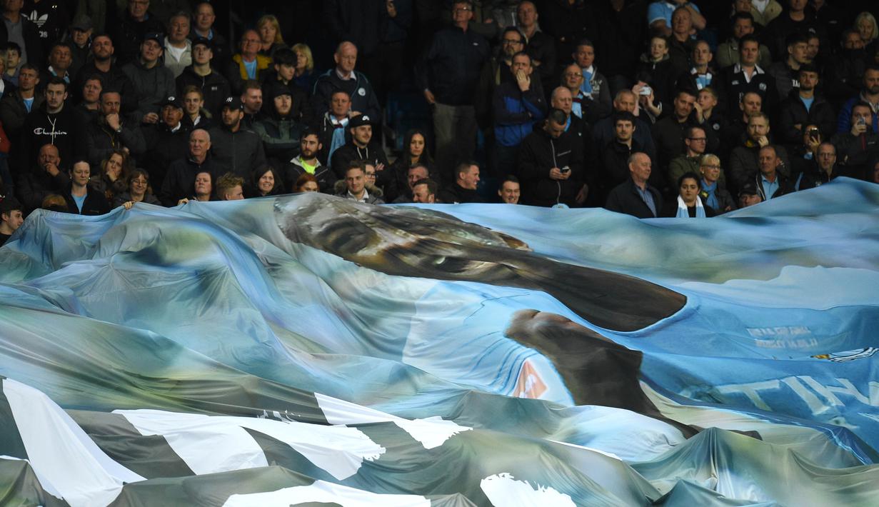 Suporter Manchester City membentangkan spanduk bergambar Yaya Toure usai laga melawan Brighton and Hove Albion di Stadion Etihad, Rabu (9/5/2018). Laga tersebut menjadi ajang perpisahan sang pemain bersama The Citizens. (AFP/Oli Scarff)