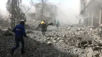 Penyelamat berlari untuk membantu korban serangan udara pasukan pemerintah di Ghouta Timur, Damaskus, Suriah, Selasa (20/2). Kelompok pemantau dan paramedis Suriah mengatakan serangan itu menewaskan 98 orang. (Syrian Civil Defense White Helmets via AP)