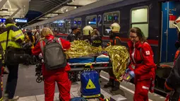 Seorang penumpang kereta yang terluka akibat dua gerbong kereta bertabrakan menerima perawatan dari tim medis di stasiun kereta api utama di Salzburg, Austria (20/4). (FMT/Wolfgang Moser/APA/AFP)