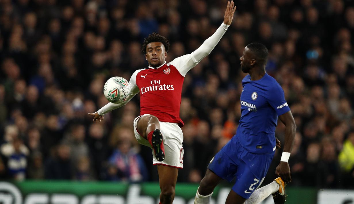 Pemain Arsenal, Alex Iwobi (kiri) menghalau bola dari kejaran pemain Chelsea, Antonio Rudiger pada laga leg pertama semifinal Piala Liga Inggris di Stamford Bridge, London, (10/01/2018). Chelsea bermain imbang 0-0 lawan Arsenal. (AFP/Adrian Dennis)