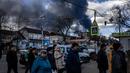 Orang-orang mengantre di depan supermarket sementara asap mengepul di atas kota Vasylkiv di luar Kiev (27/2/2022). Rudal Rusia telah menghantam pipa gas dan kilang minyak di kawasan Vasylkiv. (AFP/Dimitar Dilkof)