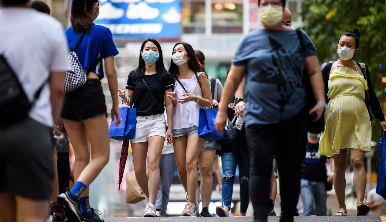 Dua wanita mengenakan masker sebagai tindakan pencegahan Covid-19 saat berjalan di Hong Kong (13/5/2020). Dua orang di Hong Kong dinyatakan positif Covid-19, mengakhiri perjalanan 24 hari tanpa kasus baru yang mulai melonggarkan peraturan jarak sosial. (AFP/Anthony Wallace)