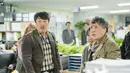 Dalam potongan gambar pertama, pejabat Balai Kota Onju sedang berkonfrontasi dengan beberapa pelapor. Lee Hong Jo tampaknya terjebak di antara ketua tim divisi Gong Seo Gu (Hyun Bong Sik) dan para pengadu yang marah. (JTBC via Soompi)