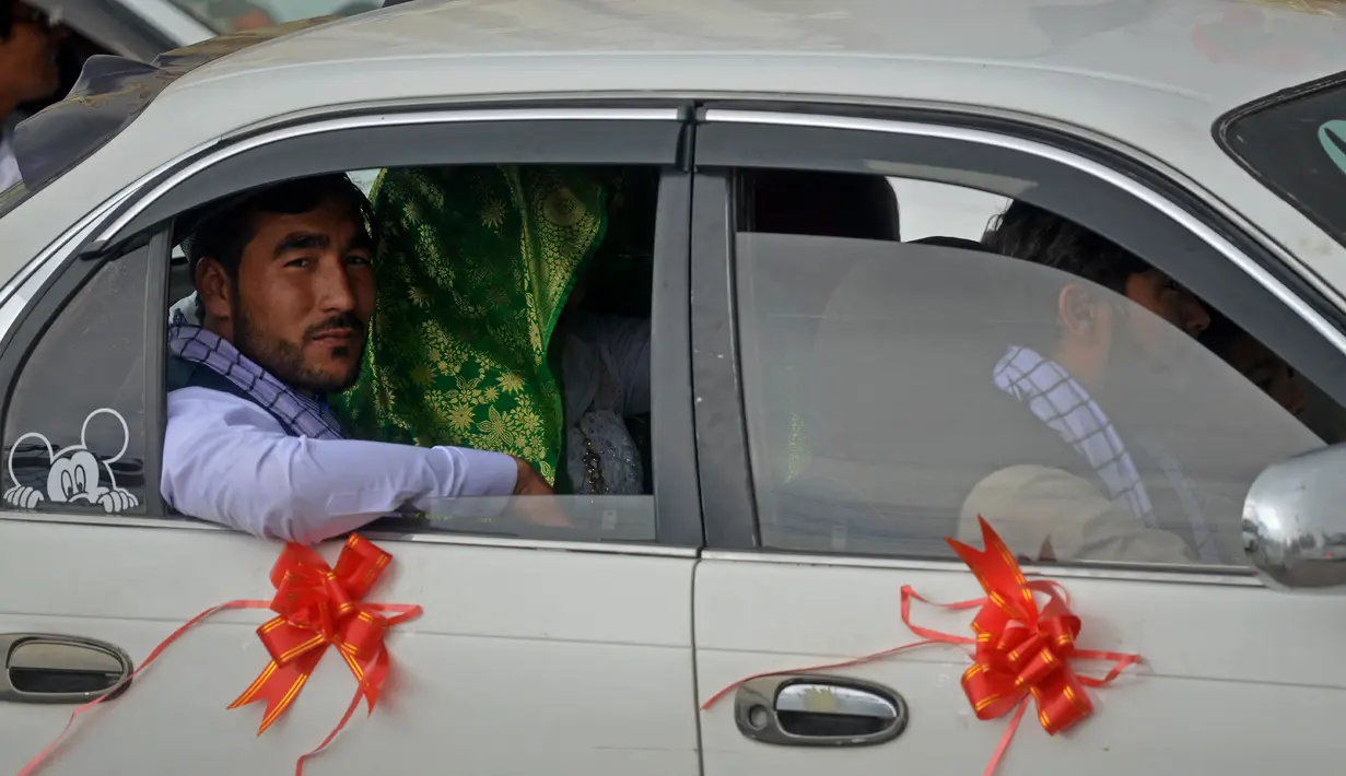 Sebuah mobil yang dihias membawa pasangan Afghanistan meninggalkan aula pernikahan setelah upacara pernikahan massal di Kabul, Afghanistan, 13 Juni 2022. Puluhan wanita Afghanistan yang disembunyikan dalam selendang hijau tebal dinikahkan dalam pernikahan massal yang ketat di Kabul. (Sahel ARMAN/AFP)