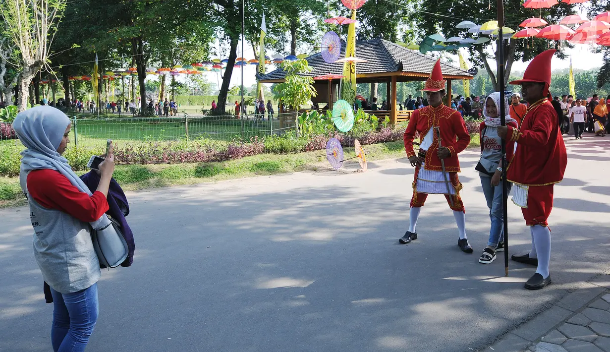 Wisatawan berfoto dengan petugas berpakaian ala mataraman di areal Candi Prambanan, Yogyakarta, Jumat (30/6). Mengisi libu panjang lebaran 2017, ribuan wisatawan dari berbagai daerah memadati kawasan Candi Prambanan. (Liputan6.com/Helmi Fithriansyah)