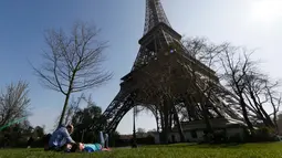 Sebuah keluarga menikmati musim semi yang hangat dan cerah di sebuah taman di dekat menara Eiffel, Paris, Kamis (9/4/2015). (REUTERS/Gonzalo Fuentes)
