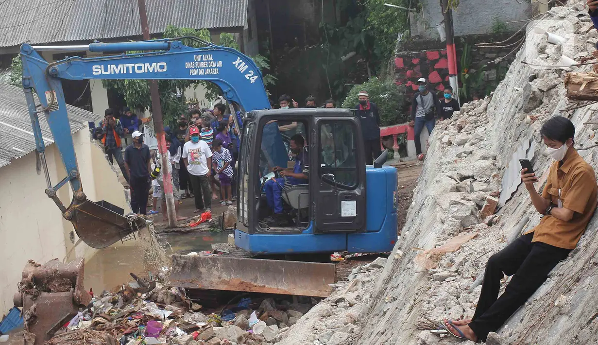 Petugas Suku Dinas Sumber Daya Air Jakarta Selatan menggunakan alat berat untuk mengeruk material pascalongsor di kawasan Ciganjur, Senin (12/10/2020). Alat berat dikerahkan mengeruk puing-puing bangunan tembok yang roboh pada kejadian longsor pada Sabtu 10 Oktober malam. (merdeka.com/Arie Basuki)