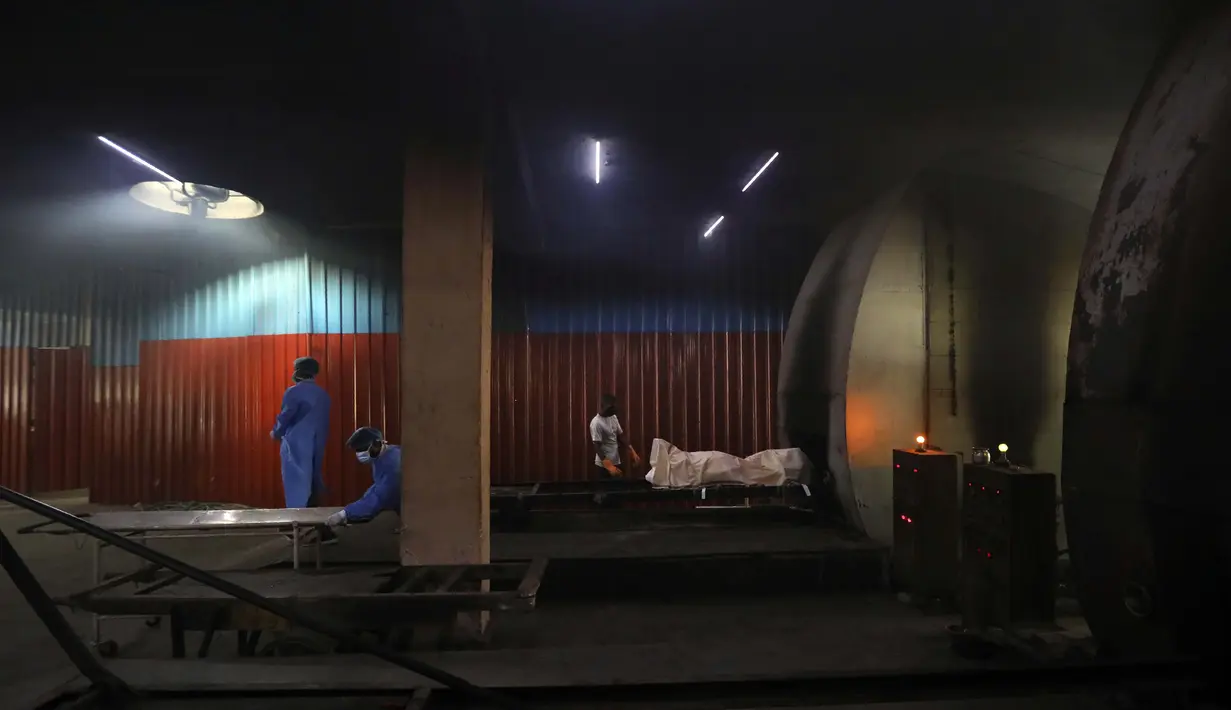 Pekerja melepas tandu saat orang lain bersiap untuk mengkremasi jenazah korban COVID-19 di New Delhi, India, Rabu (16/9/2020). Total infeksi virus corona di India melewati 5 juta pada Rabu (16/9). (AP Photo/Manish Swarup)
