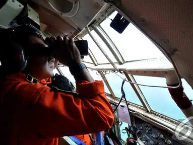Seorang anggota TNI AU meneropong dari dalam pesawat saat melakukan pencarian AirAsia QZ8501, Perairan Pangkalan Bun, Kalimantan, Selasa (30/12/2014). (Liputan6.com/Miftahul Hayat)