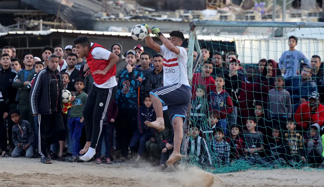 Pemuda Palestina bermain sepak bola di kamp pengungsi sebelum berbuka puasa selama bulan suci Ramadhan di Rafah, di Jalur Gaza selatan (11/4/2022). Sepanjang bulan, umat Islam yang taat harus berpantang dari makanan dan minuman dari fajar hingga matahari terbenam. (AFP/Said Khatib)