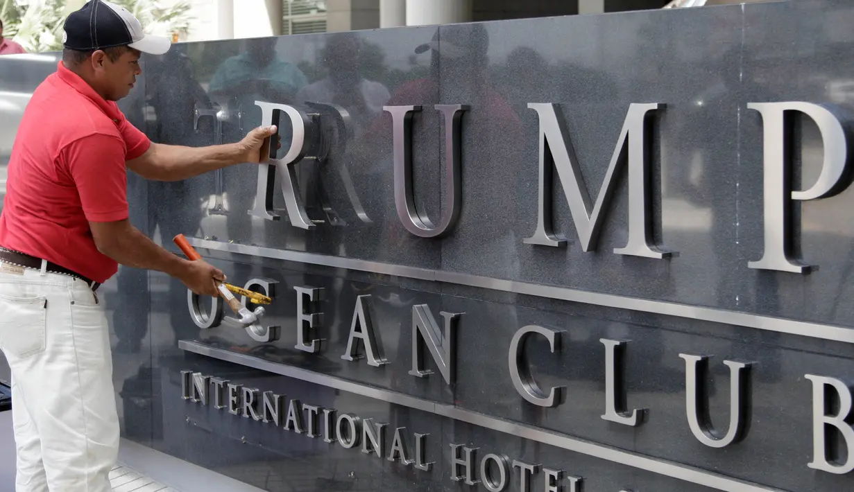 Pekerja mencopot nama 'Trump' dari papan hotel mewah, Ocean Club International Hotel and Tower di Panama, Senin (5/3). Pencabutan dilakukan pemilik bangunan yang mengatakan segera menyingkirkan keluarga Trump dari pengelolaan gedung. (AP/Arnulfo Franco)